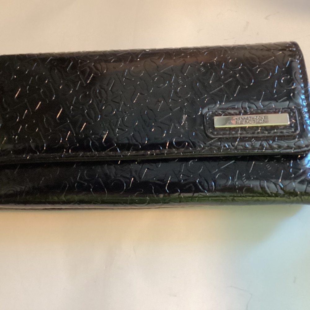 Kenneth Cole Reaction Trifold Wallet in Black with “KC” embossed on the surface